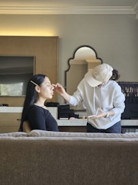 a woman getting her makeup done in a hotel room