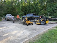 a lawn mower is parked next to a truck in a driveway