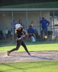 a softball player swings at a ball during a game