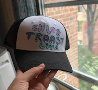 a person holding up a hat that says chloe toast live