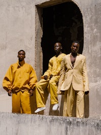 three men in yellow suits standing on a wall