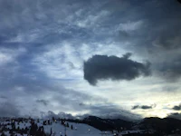 a cloud is seen in the sky over a ski resort
