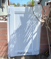 a white gate in a yard with a tree in the background