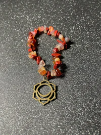 a bracelet with an orange stone and a brass charm