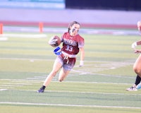 a girl running with a football on a field