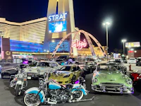classic cars and motorcycles parked in front of the las vegas sign
