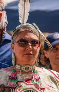 a woman wearing a feathered headdress and sunglasses