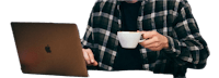 a man in a plaid shirt holding a cup of coffee in front of a laptop