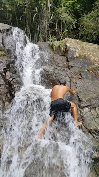 a man climbing up a waterfall in the jungle