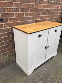 a white sideboard with drawers in front of a brick wall