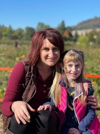 a woman and a little girl posing for a picture in a pumpkin patch