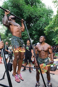 a group of men doing pull ups in a park