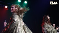 two women on stage with microphones