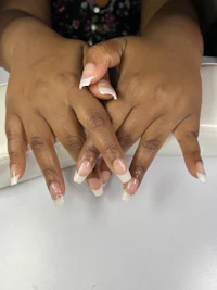 a woman's hands with white nail polish on them