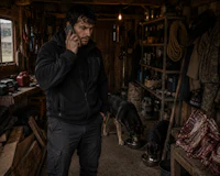a man talking on a cell phone in a shack