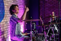 a young man playing drums in front of a brick wall