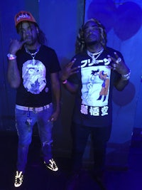 two men standing next to each other wearing t - shirts