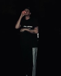 a man standing in the dark with a cigarette in his hand