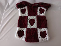 a burgundy and white knitted sweater on a bed