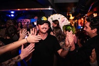 a man in a hat with his hands up at a party