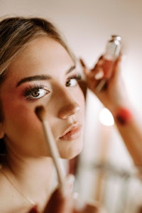 a woman is getting her makeup done in front of a mirror