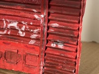 a piece of red corrugated cardboard with paint on it