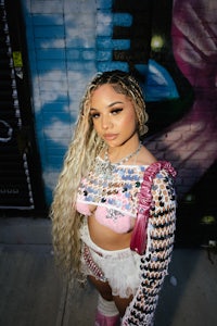 a woman in a pink outfit standing in front of a graffiti wall