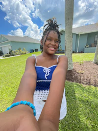 a young girl in a blue top and white shorts is taking a selfie