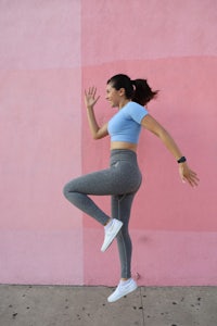 a young woman is jumping in front of a pink wall