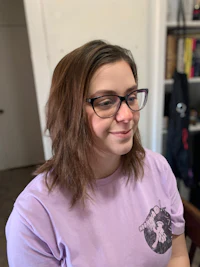 a young woman wearing glasses and a purple t - shirt