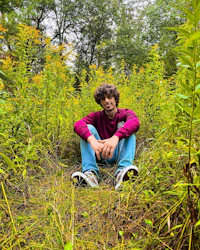 a young man sitting in the middle of a field