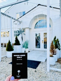 a person holding up a black and white card in front of a house