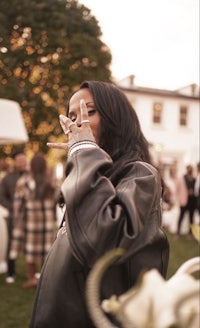 a woman in a leather jacket is holding a cigarette