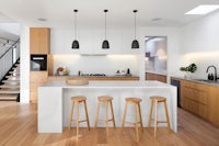 a modern kitchen with wooden floors and stools