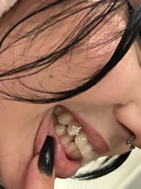 a woman with black hair and black teeth is putting her finger in her mouth