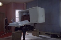 a man is sitting on top of a refrigerator in a room