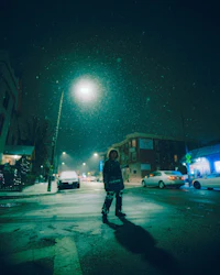 a person standing on a snowy street at night