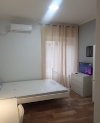 a small bedroom with a bed, desk and tv