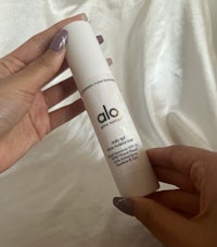 a person holding a bottle of alo face serum