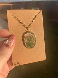 a person holding a necklace with a green stone on it