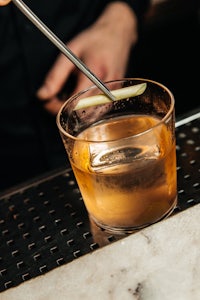 a bartender pouring a cocktail into a glass