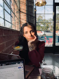 a woman sitting at a table with a laptop and a drink