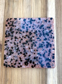 a pink and black stone coaster on a wooden table