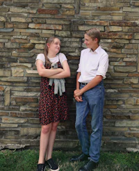 a man and a woman standing in front of a stone wall