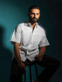 a man in a white shirt sitting on a stool