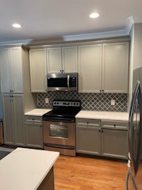 a kitchen with gray cabinets and stainless steel appliances