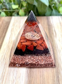 a glass pyramid with red and brown stones on top