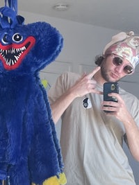 a man holding a blue stuffed animal in front of a mirror