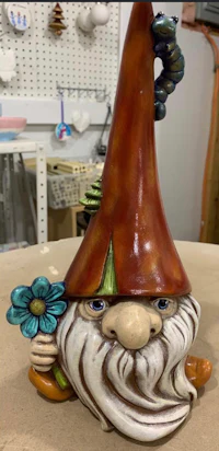 a ceramic gnome with a flower on his head