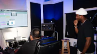 two men in front of a monitor in a recording studio